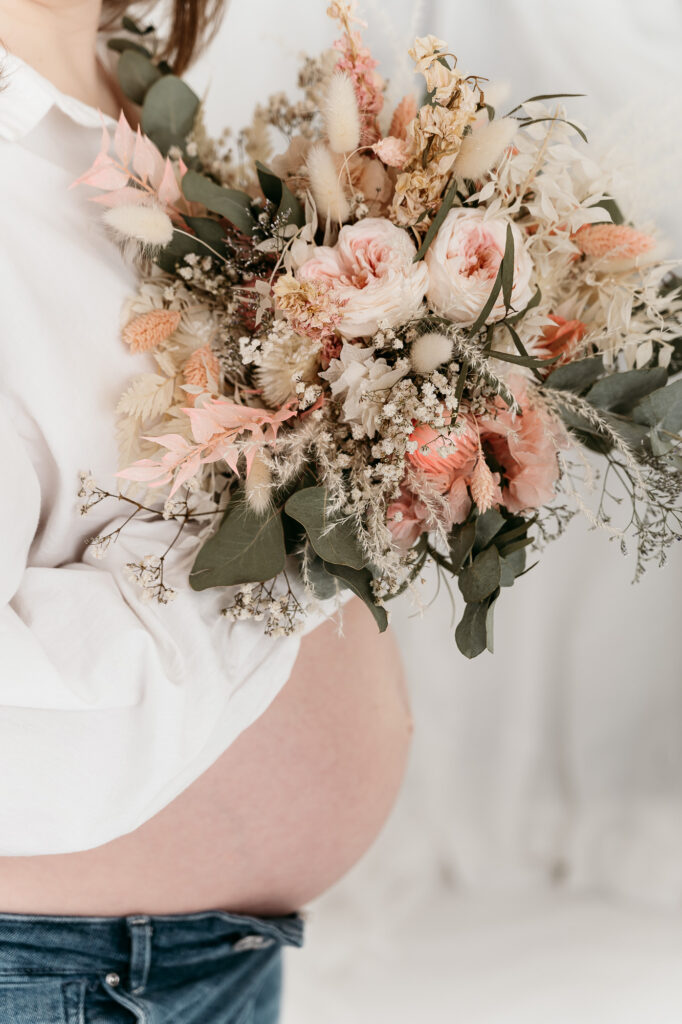 Schwangerenfotos mit Blumenbouquet für ein Fotoshooting zeitlos zu Hause bei Freilassing