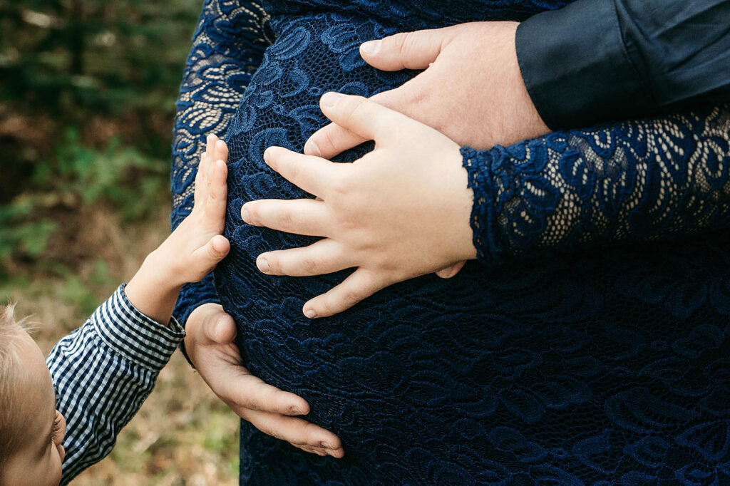 Babybauch und Kinderhände bei einem Shooting im Wald bei Bad Reichenhall